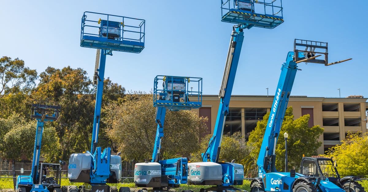 pexels-photo-16105409-16105409 Outdoor scene with multiple blue aerial lifts and heavy machinery in a sunny industrial area.