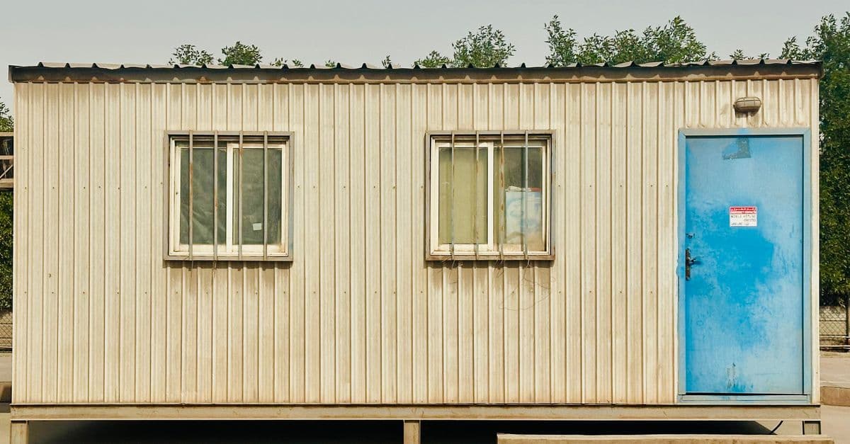 pexels-photo-35385946-35385946 A portable cabin with a distinctive blue door in a sunny outdoor setting in Saudi Arabia.