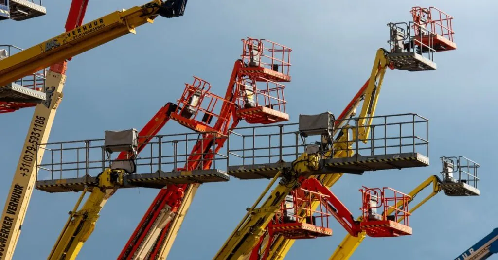 pexels-photo-32114503-32114503 Vibrant boom lifts reaching skyward, showcasing industrial machinery against a clear blue backdrop.