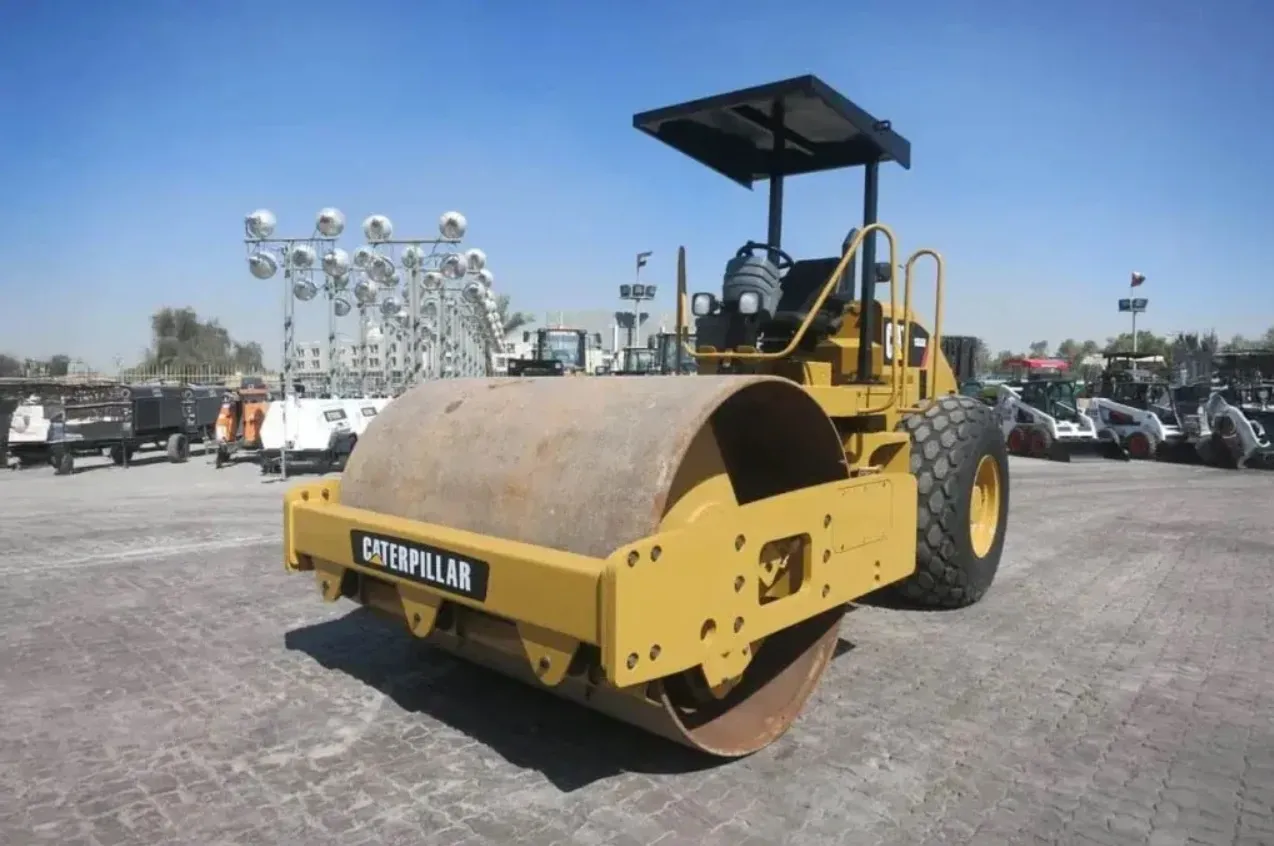 Road Roller Hire Abu Dhabi – Heavy Equipment Rental Heavy-duty Caterpillar road roller parked at a machinery yard available for road roller hire Abu Dhabi